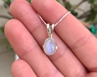 Può includere: Una collana a catena d'argento con un delicato ciondolo ovale in pietra di luna.