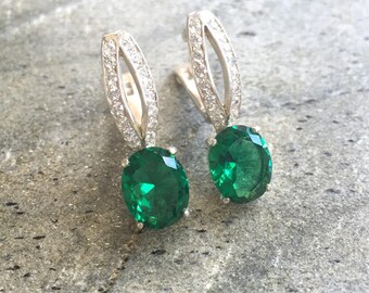 May include: A pair of silver earrings with a green oval gemstone and a row of clear cubic zirconia stones.