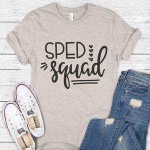 May include: A beige t-shirt with the text "SPED squad" in black lettering. The shirt is styled with a pair of distressed blue jeans and white sneakers.