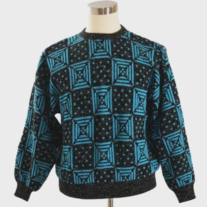 May include: A black and teal geometric pattern sweater. The sweater features a repeating square design in teal against a black background. The collar, cuffs, and hem are a darker gray. The sweater is displayed on a mannequin.