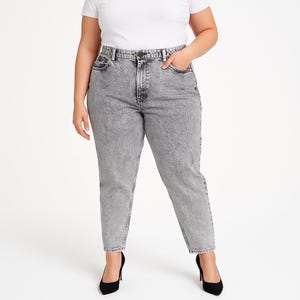 May include: Acid wash gray denim jeans with a high waist and a classic five-pocket design. The jeans have a straight leg and are paired with black high heels. The model is wearing a white t-shirt.