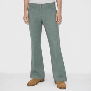 May include: Light green flared pants with a classic five-pocket design. The pants have a button and zipper closure and are made of a durable fabric. The pants are paired with brown suede shoes.