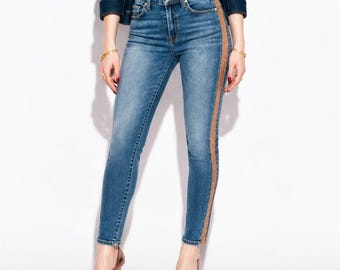 May include: Blue denim jeans featuring a high-waisted fit, a classic five-pocket design, and a vertical metallic gold glitter stripe running down the outer side of each leg. The jeans have a slim silhouette and a standard button and zipper closure.