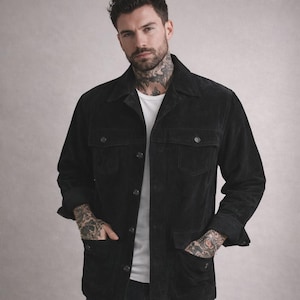 May include: Black corduroy jacket with a button-up front, two chest pockets, and two lower pockets. The jacket has a classic collar and long sleeves. The model is wearing a white t-shirt underneath.