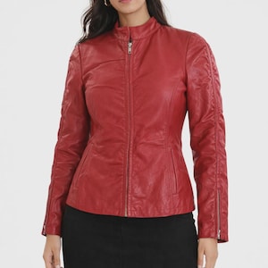 May include: A red leather jacket with a stand-up collar and a zipper closure. The jacket has zippered sleeves and a fitted silhouette. The jacket is a solid red color.