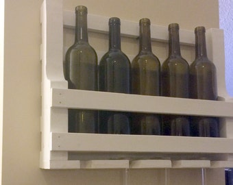May include: White wooden wine rack with two shelves and six wine bottles. The rack also has four glass holders underneath.