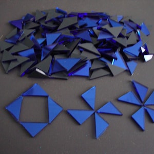 May include: A pile of blue glass mosaic tiles, some are arranged in a square shape and others are arranged in a star shape.