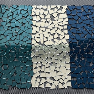 May include: Three sections of broken mirror tiles. The left section is teal green, the middle section is silver, and the right section is dark blue.