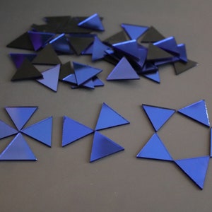 May include: A collection of blue and black triangular mirror tiles. Some of the tiles are arranged in the shape of a star and a pinwheel.
