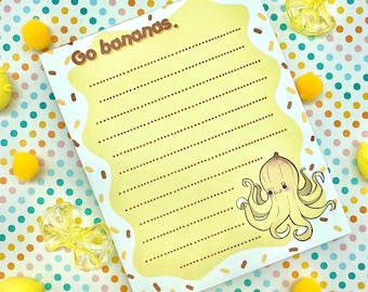 May include: A yellow lined notepad with the text "Go bananas." printed on the front. A cartoon banana with a face and octopus tentacles is illustrated on the bottom right corner of the notepad.