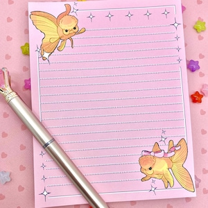 May include: Pink stationery paper with a lined design. The paper features two illustrations of goldfish with a pink bow and a butterfly. The paper has a white border and stars.