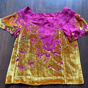 May include: A short-sleeved top featuring a vibrant magenta base with a tonal floral pattern and a contrasting mustard yellow velvet overlay. The velvet fabric is applied in an organic, asymmetrical floral design across the front and sleeves.