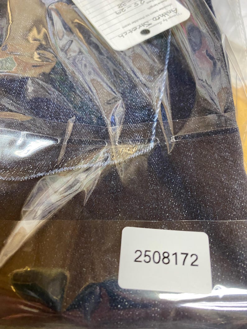 May include: Dark blue denim trousers in a clear plastic bag. A white tag with the text "Anthro Stretch" is visible. A white sticker with the number "2508172" is also visible.