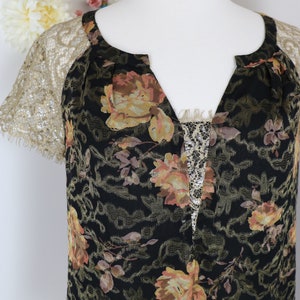 Puede incluir: Vestido negro con estampado floral, cuello en V y mangas de encaje. El vestido presenta un patr&oacute;n de rosas amarillas y melocot&oacute;n y un panel de encaje en el escote. Las mangas son de encaje dorado delicado.