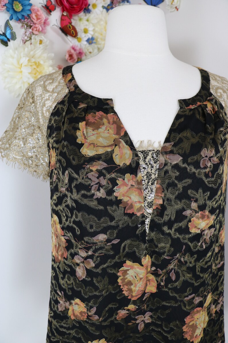 Puede incluir: Vestido negro con estampado floral, cuello en V y mangas de encaje. El vestido presenta un patr&oacute;n de rosas amarillas y melocot&oacute;n y un panel de encaje en el escote. Las mangas son de encaje dorado delicado.