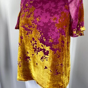 May include: A short-sleeved top featuring a square neckline and a vibrant floral pattern. The garment is constructed from a combination of magenta sheer fabric and textured mustard yellow velvet, creating a distinct contrast in both color and material.