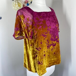 May include: A short-sleeved top featuring a square neckline and a two-tone design. The garment is crafted from a velvet-textured fabric with a floral pattern, transitioning from a deep magenta color at the top to a rich mustard gold at the bottom.