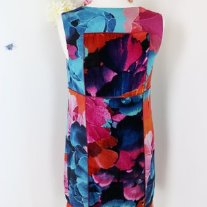 Pode incluir: Vestido sem mangas com um padr&atilde;o floral vibrante em tons de azul, rosa e laranja. O vestido apresenta um design de patchwork com uma estampa arrojada e colorida. O vestido &eacute; exibido em um manequim, mostrando sua forma e design.