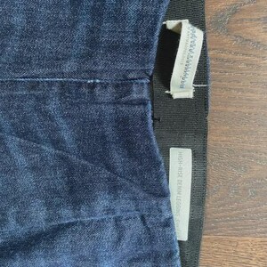 May include: Close-up of dark blue denim leggings. The leggings have a high-rise waist and a black elastic waistband. A white tag with the text "ANTHROPOLOGIE" is attached to the waistband. Another tag reads "HIGH-RISE DENIM LEGGING".