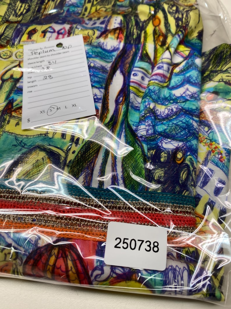 May include: A colourful, abstract-patterned top in a clear plastic bag. The top features a vibrant mix of blues, greens, yellows, and oranges. A tag indicates the shoulder seam to shoulder seam is 86 cm, and the length is 58 cm.