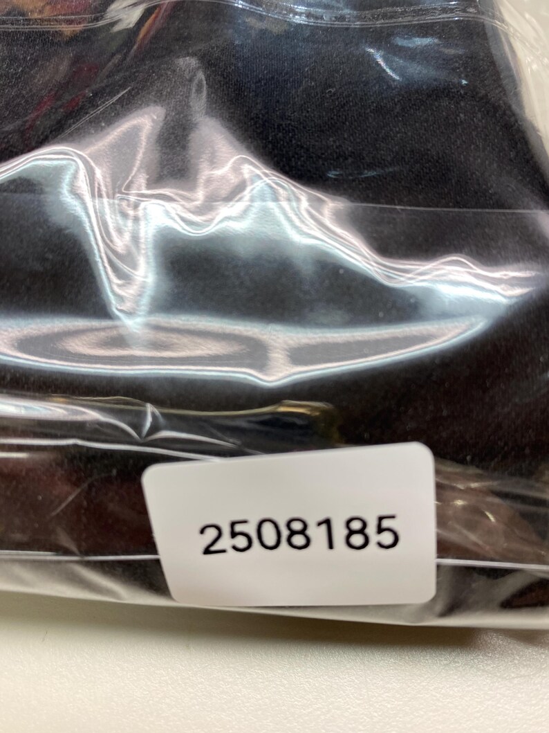 May include: A black item is sealed inside a clear plastic bag. A white sticker with the number "2508185" is visible on the bag.