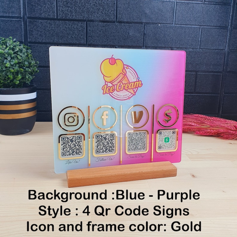 May include: A decorative sign for an ice cream shop with a blue and purple gradient background. It features gold icons for Instagram, Facebook, Venmo, and a payment app, each with a QR code. The sign is mounted on a wooden base.