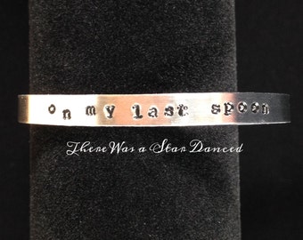 Puede incluir: Una pulsera de metal plateado con las palabras "on my last spoon there was a star danced" grabadas.