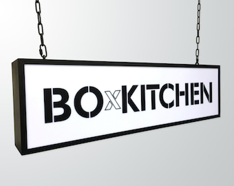 May include: Black and white sign with the text "BOXKITCHEN" hanging from a chain.