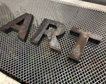 May include: The word "ART" spelled out in large, rusty metal letters on a metal grate background.