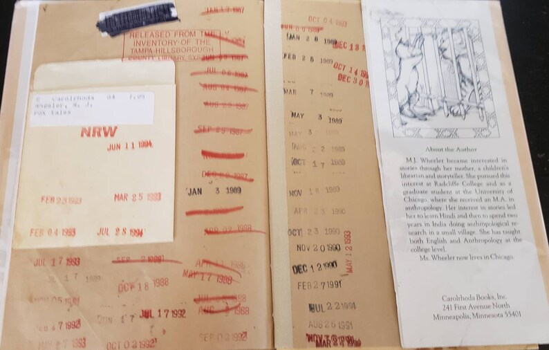 May include: A close-up of a book's back cover with a red stamp that says "Released from the Inventory of the Tampa Hillsborough County Library System". The book's title is "About the Author" and the text describes the author's interest in storytelling and her studies in anthropology. The book is published by Carolrhoda Books, Inc. 241 First Avenue North Minneapolis, Minnesota 55401.