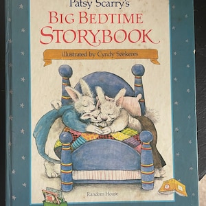May include: A blue book with a white cover and the title "Patsy Scarry's Big Bedtime Storybook" illustrated by Cindy Szkeres. The book features a picture of two white bunnies sleeping in a blue bed with a colorful patchwork quilt.