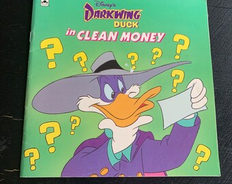 Puede incluir: Una portada de libro verde con el título "Disney's Darkwing Duck in Clean Money" y una imagen de dibujos animados de Darkwing Duck con un traje morado y un sombrero, sosteniendo un trozo de papel con signos de interrogación a su alrededor.