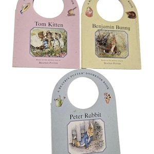 May include: Three Beatrix Potter door knob books. The books are pink, yellow, and blue. The books feature Tom Kitten, Benjamin Bunny, and Peter Rabbit. Each book has a hole in the center for a door knob.