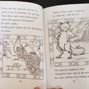May include: A black and white illustration of a peacock and a fox. The peacock is standing on the ground with its tail feathers spread out. The fox is standing on its hind legs with its paws on its hips. The text "Bones always take a long time to come up," said the fox." is written below the fox.