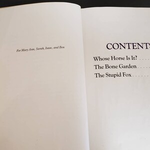 May include: A book titled "Whose Horse Is It?" with a table of contents listing three stories: "Whose Horse Is It?", "The Bone Garden", and "The Stupid Fox".