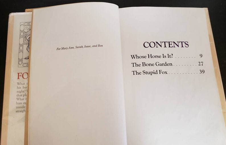 May include: A book titled "Whose Horse Is It?" with a table of contents listing three stories: "Whose Horse Is It?", "The Bone Garden", and "The Stupid Fox".