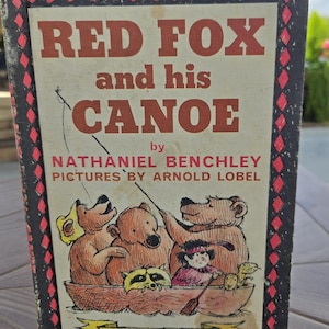May include: A vintage children's book cover with a red and black border. The title is "Red Fox and his Canoe" by Nathaniel Benchley. The illustrations are by Arnold Lobel and depict a red fox and other animals in a canoe.