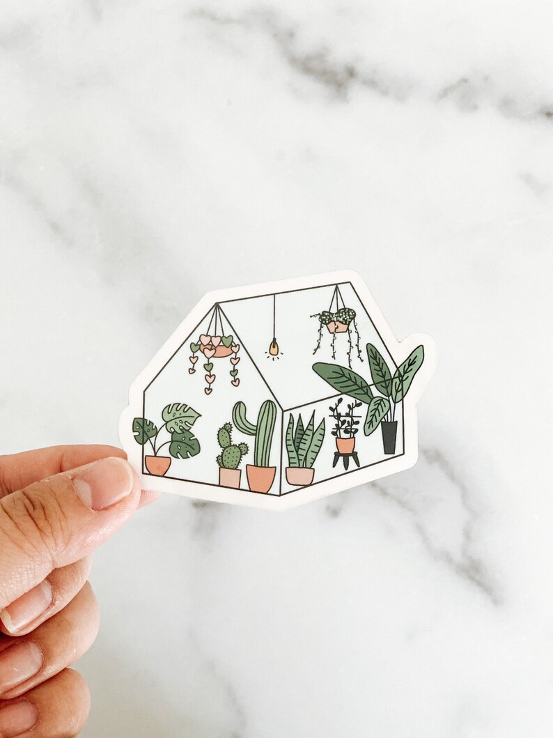 May include: A white sticker with a black outline of a greenhouse filled with various plants, including cacti, succulents, and leafy plants. The greenhouse has a light bulb and a hanging plant with pink hearts.