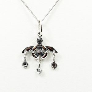 Può includere: Una collana d'argento con un ciondolo che presenta un design dettagliato con accenti neri e tre pietre pendenti.