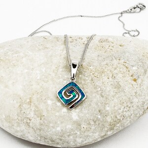 May include: A silver chain necklace with a blue and green opal pendant featuring a spiral design.
