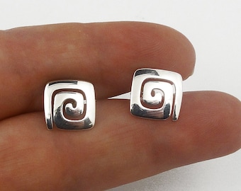 May include: A pair of square, silver-toned stud earrings. Each earring features a spiral design within a square frame. The earrings are displayed against a plain white background.