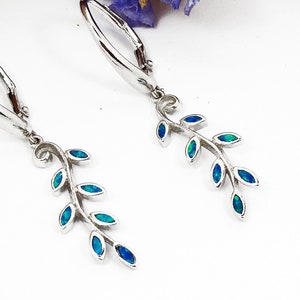 Könnte beinhalten: Ein Paar silberne Ohrringe mit einem zarten Zweigdesign. Jeder Zweig ist mit blauen Opal-Steinen verziert.