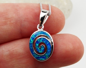 Könnte beinhalten: Halskette mit ovalem Silberanhänger. Der Anhänger hat einen blau-grünen Opalstein mit Spiralmuster. Der Anhänger ist etwa 2 cm lang und 1,3 cm breit.