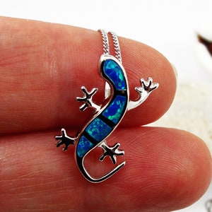 May include: A silver necklace with a blue opal lizard pendant. The lizard is detailed with silver accents and has a blue opal body.