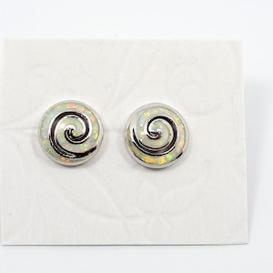May include: A pair of silver stud earrings with a white opal swirl design.