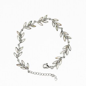 May include: A silver bracelet featuring a delicate design of leaves, each leaf is accented with a white opal stone.