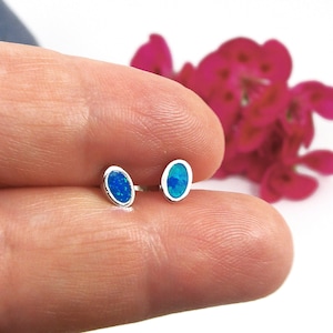 Puede incluir: Un par de pendientes de plata con piedras de ópalo azul de forma ovalada.