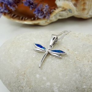 Puede incluir: Collar con colgante de lib&eacute;lula de plata con detalles de &oacute;palo azul. La lib&eacute;lula es un s&iacute;mbolo popular de transformaci&oacute;n y cambio.