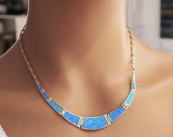 May include: A gold necklace with a curved design featuring blue opal stones.