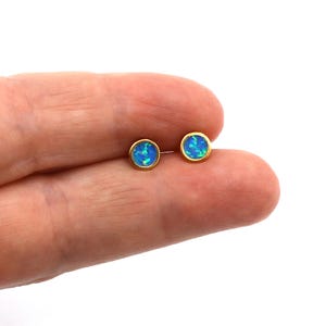 May include: A pair of gold stud earrings with blue opal stones.